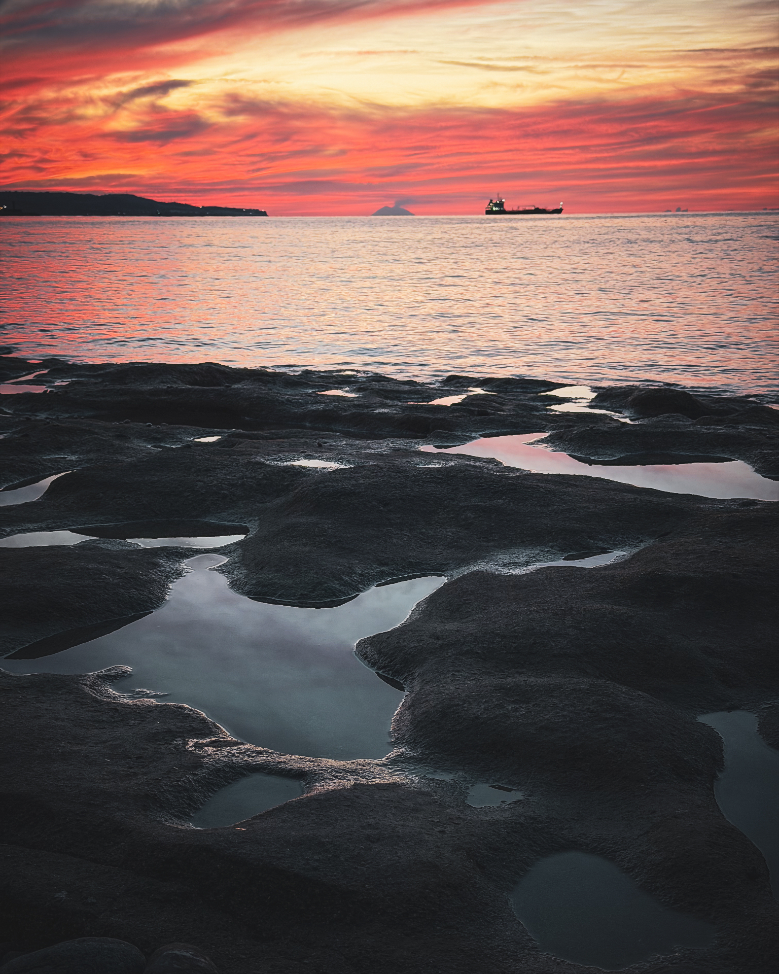 Tramonto sul Tirreno alla fine del Kalabria Coast to Coast, con scogli e pozze in primo piano