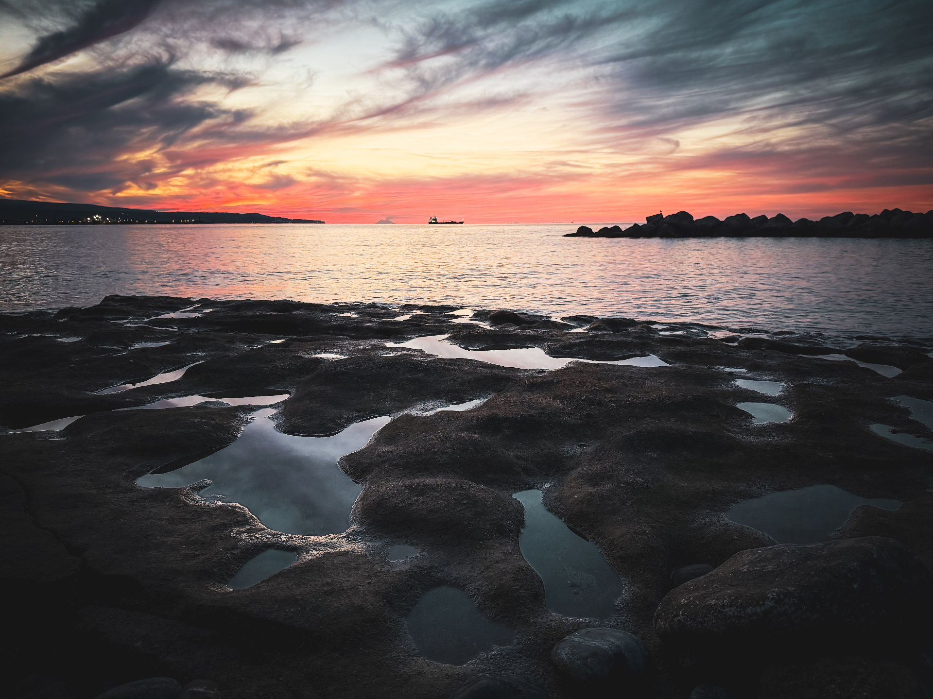 Ultima luce sul mare a Pizzo con cielo rosato e riflessi sulle rocce