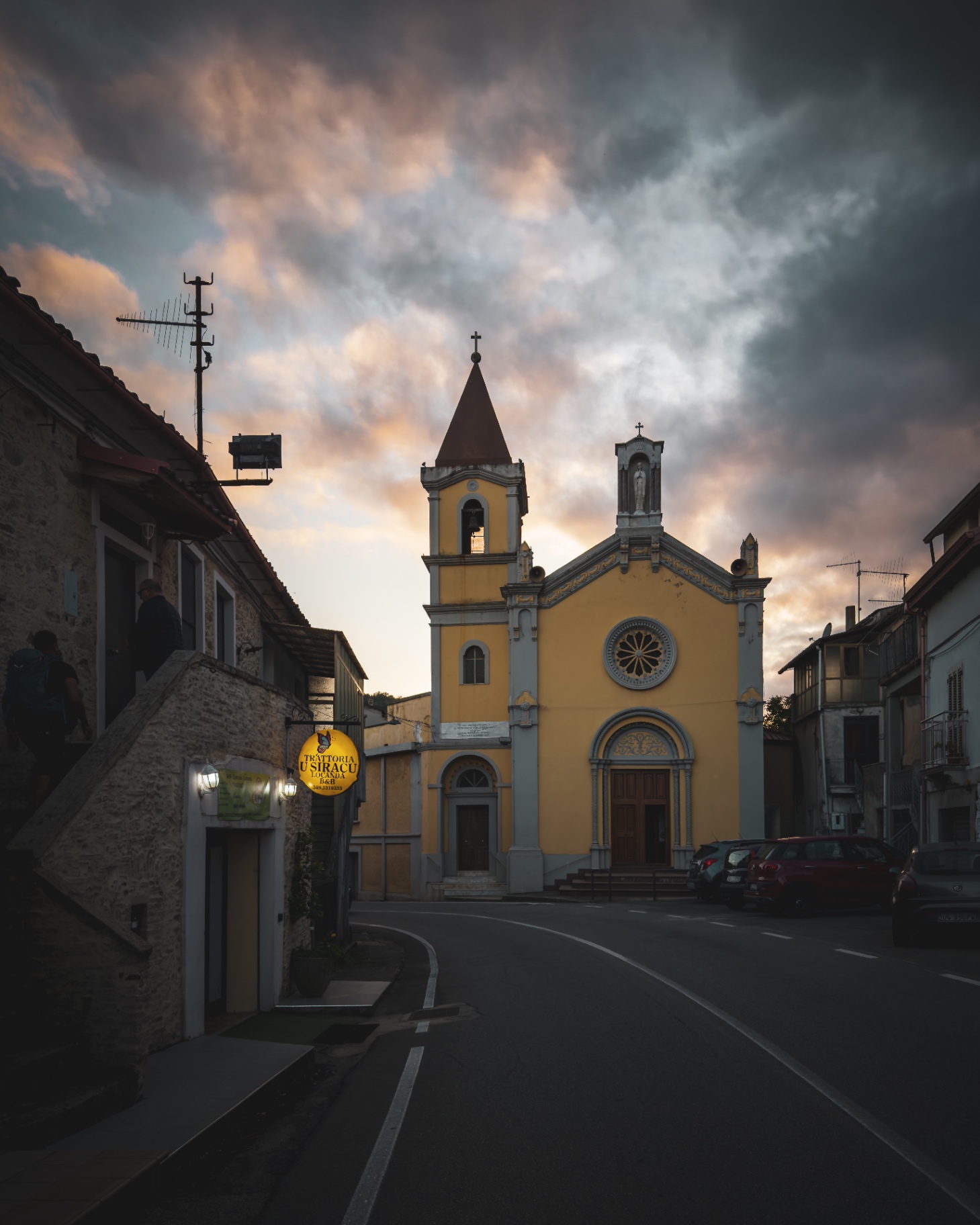 Chiesa gialla di un borgo calabrese al tramonto, con cielo acceso